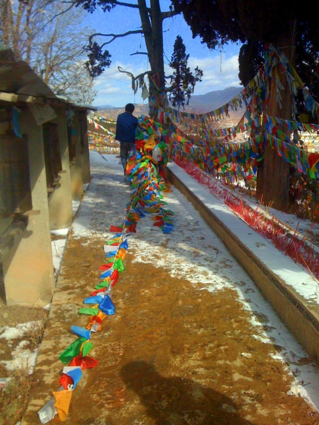 From a hilltop monastery overlooking the old part of Shangril-La below, a monk collects old prayer flags to burn.