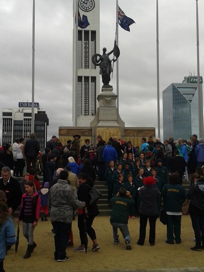 Community members gathering around the war memorial after the ceremony